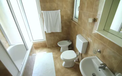 Bathroom equipped with a bathtub, sanitary ware, and beige wall tiles. - image 5