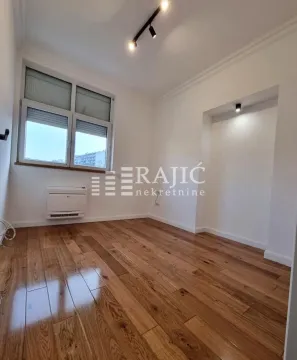 Empty room with wooden flooring, white walls, and a window. - image 10