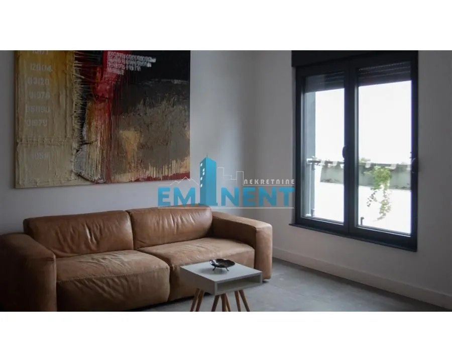 Living room with a leather sofa, coffee table, and a large artwork on the wall.