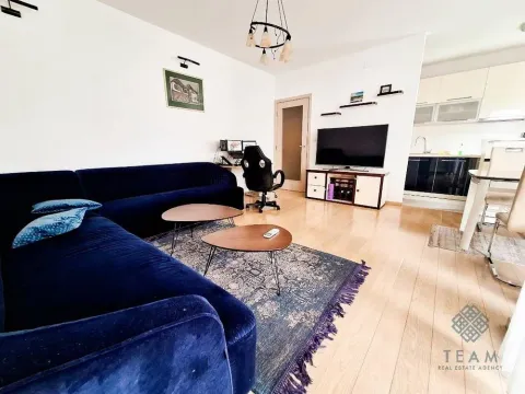 Living room with a sofa, TV, and an open layout connecting to the kitchen area. - image 2