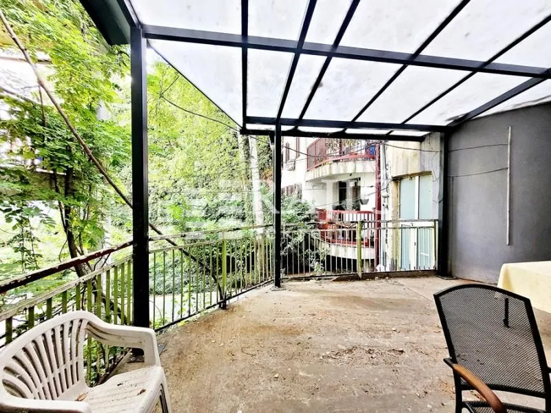 Covered terrace with a metal structure and a view of greenery.