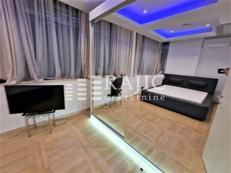 Modern bedroom with a double bed, mirrored wardrobe, and decorative lighting.