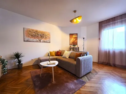 Comfortable living room with a corner sofa, parquet flooring, and decorative paintings on the wall. - image 2