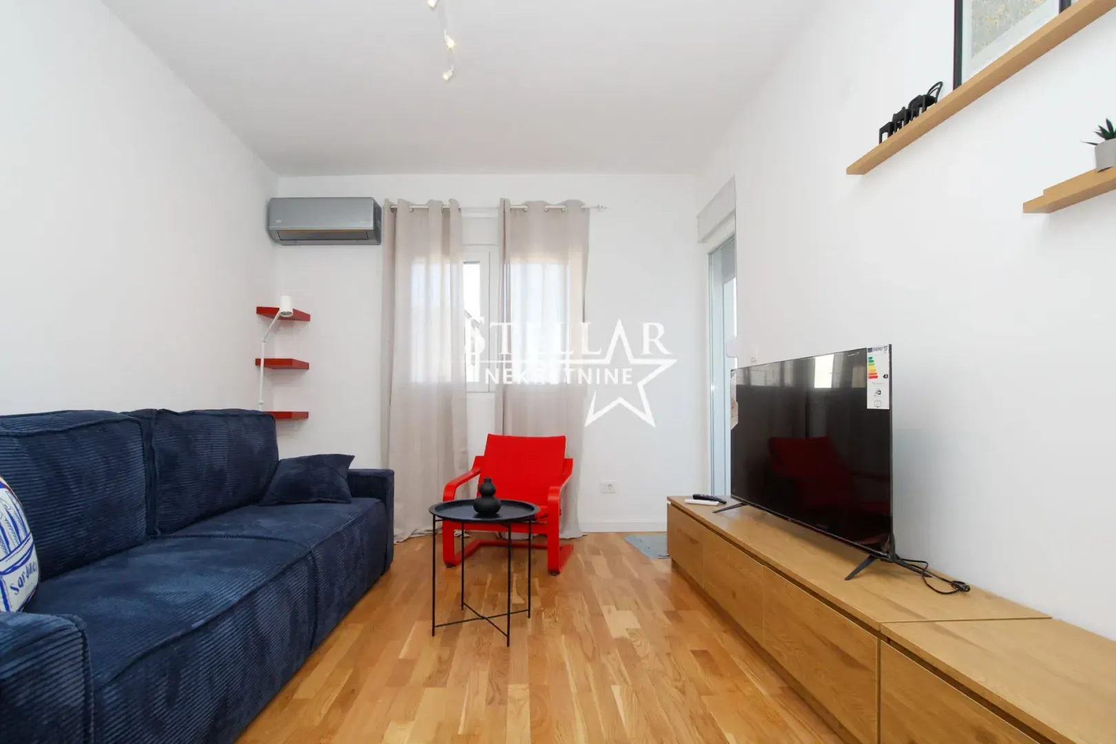Living room with a blue sofa, a red armchair, and a TV.