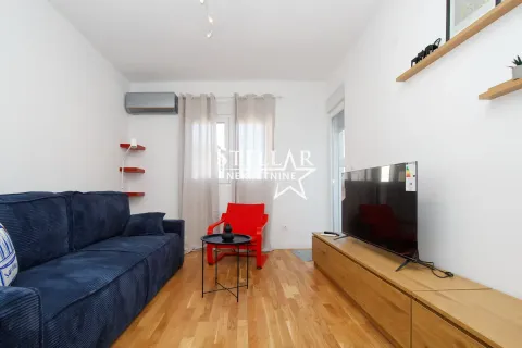 Living room with a blue sofa, a red armchair, and a TV. - image 2