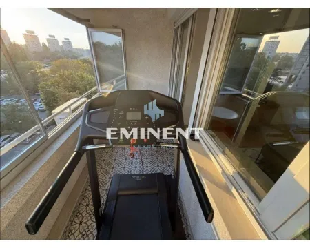 Enclosed balcony with a treadmill and city view. - image 18