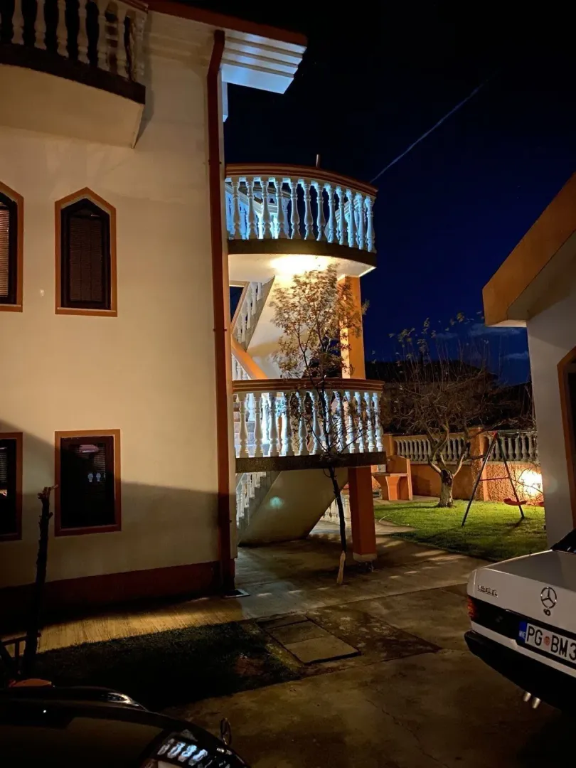 Osvijetljeno spoljašnje stepenište i dio dvorišta kuće tokom noći.