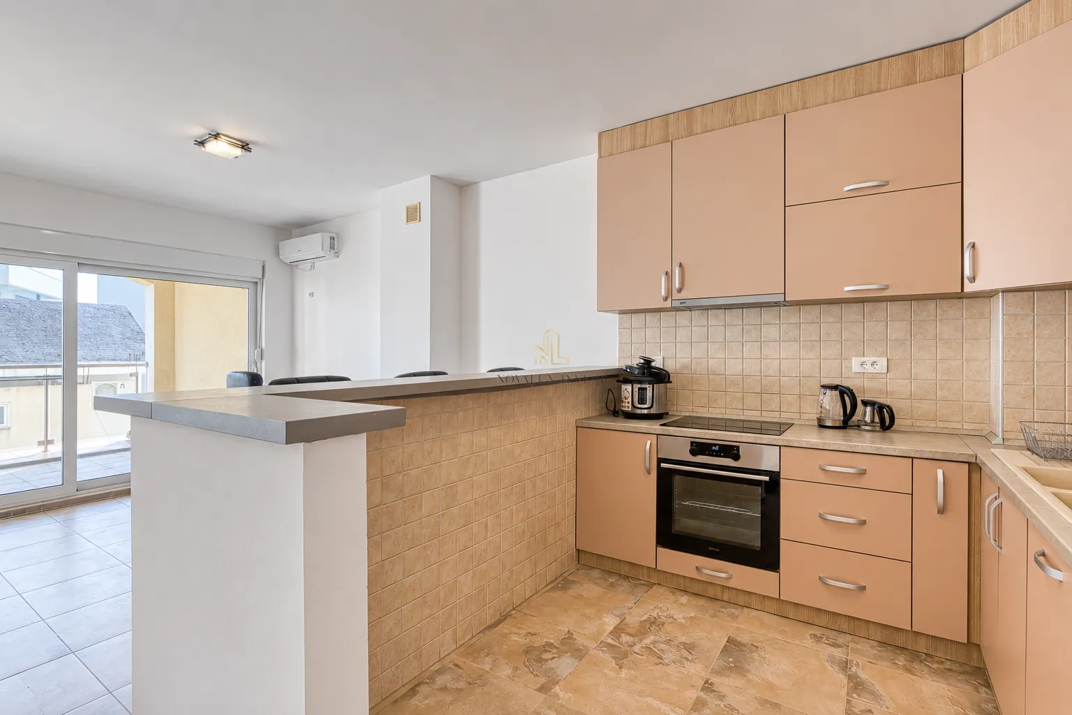 Kitchen with peach-colored cabinets and a breakfast bar separating it from the living area.
