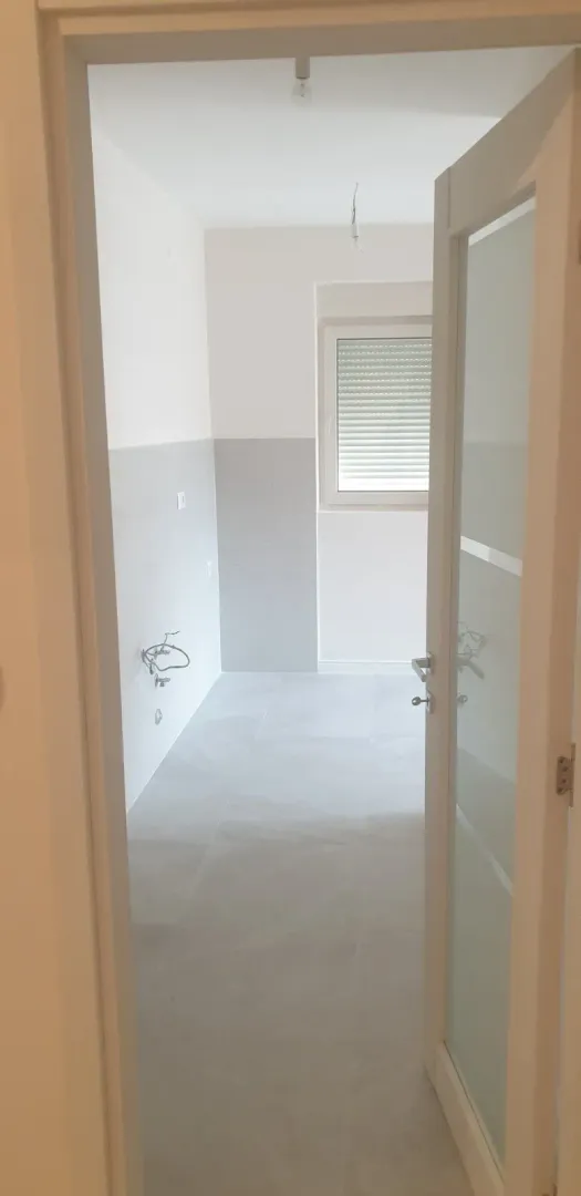 An empty room with tiles seen through an open door.