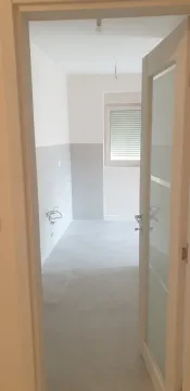 An empty room with tiles seen through an open door. - image 3