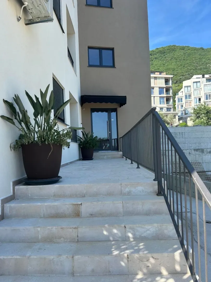 Building entrance with stairs and potted plants.