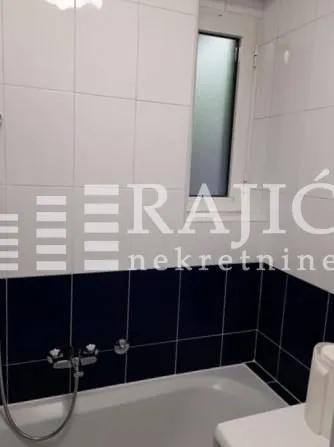 View of the bathroom with a bathtub and white tiles.