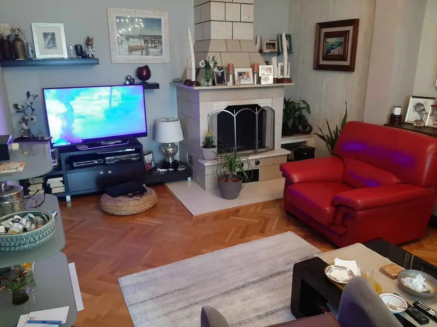 Dnevna soba sa kaminom, televizorom i crvenom kožnom foteljom.