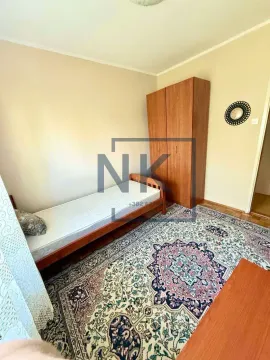 Small bedroom with a bed, wooden wardrobe, and a rug. - image 7