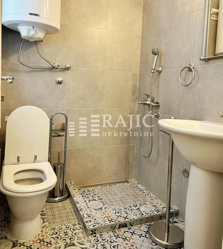Smaller bathroom with a shower enclosure, toilet, and sink.
