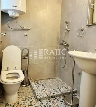 Smaller bathroom with a shower enclosure, toilet, and sink. - image 2
