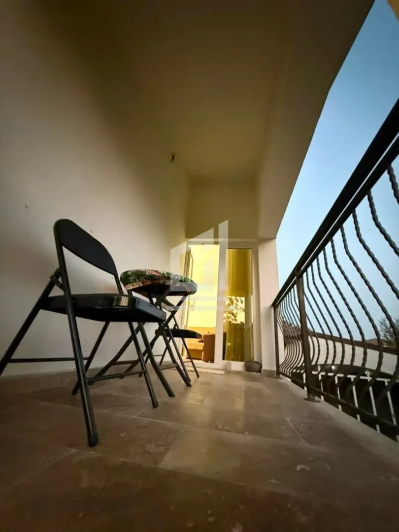 Covered balcony with chairs and a metal railing.