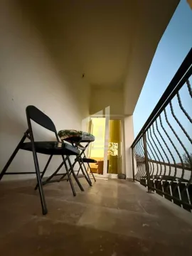 Covered balcony with chairs and a metal railing. - image 9