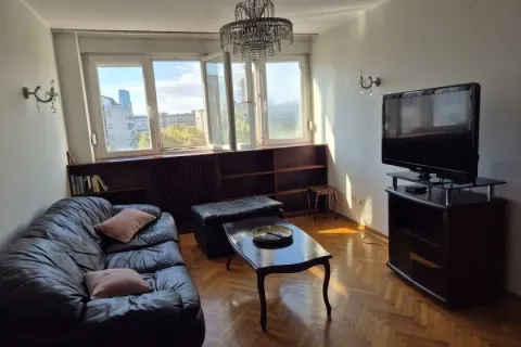 Living room with a leather sofa, television, and a large window. - image 13