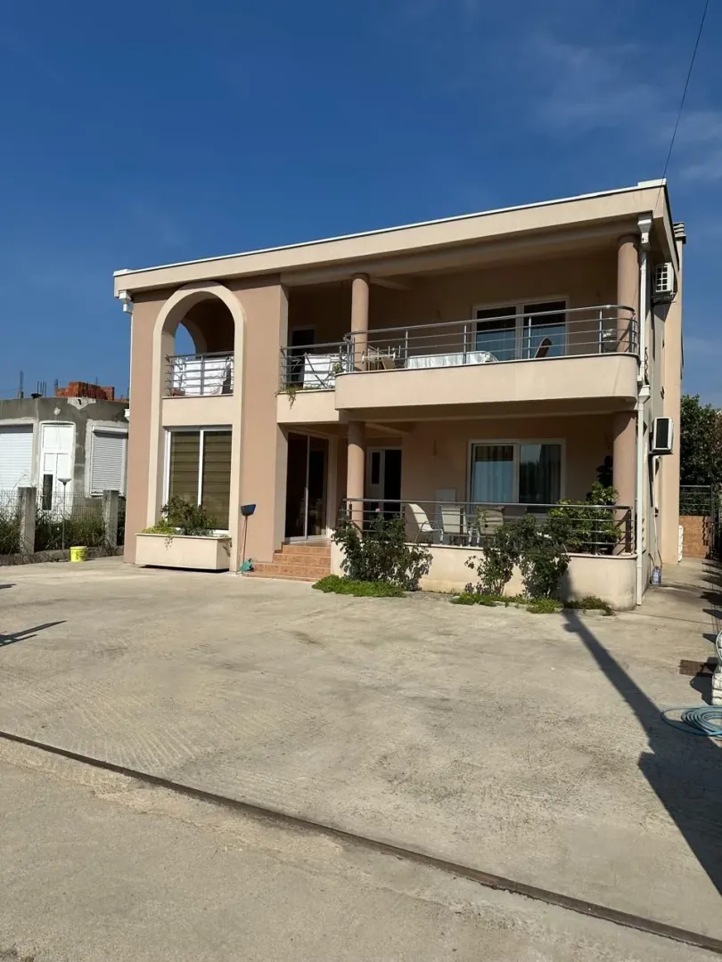 Exterior of a two-story house with terraces and a spacious paved yard.