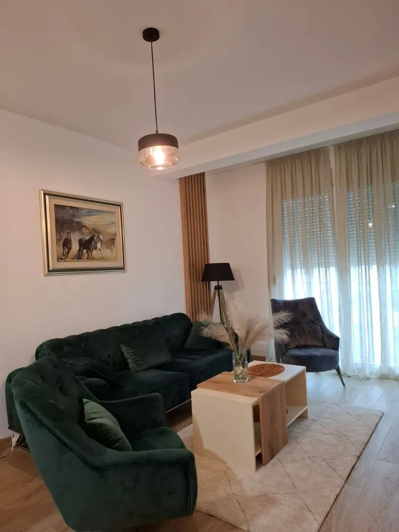 Dnevni boravak sa zelenom garniturom, foteljom i stolićem.