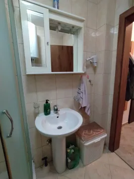 A simple bathroom featuring a white pedestal sink, a mirror, and a wall cabinet. - image 2