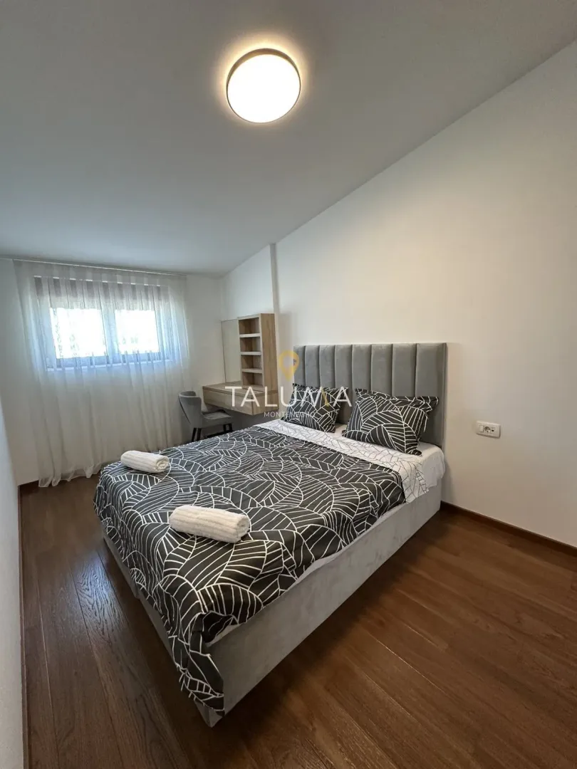 Namještena spavaća soba sa bračnim krevetom, radnim stolom i prozorom.