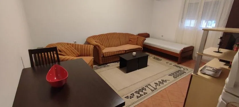 Dnevna soba sa garniturom, trpezarijskim stolom i krevetom.