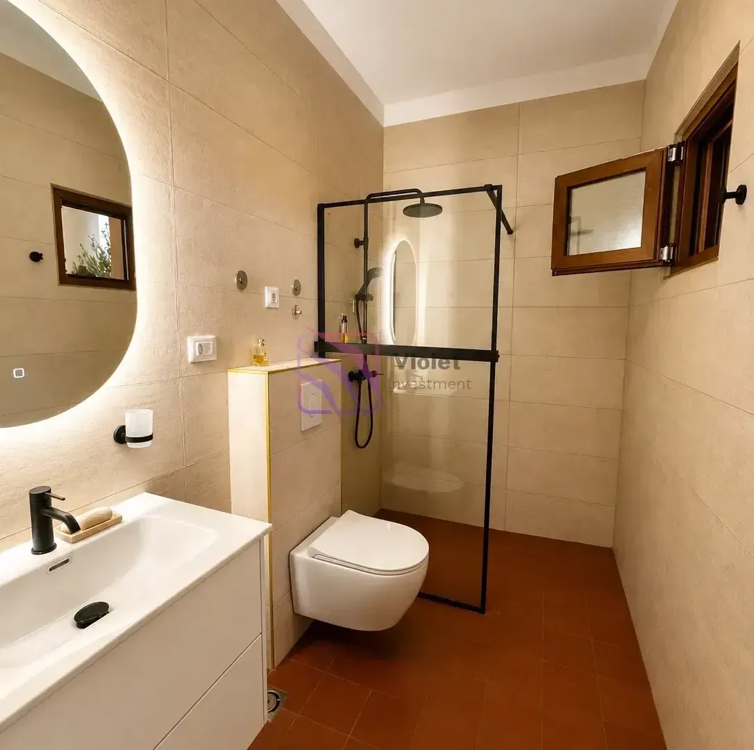Modern bathroom with a walk-in shower, washbasin, and wall-hung toilet.