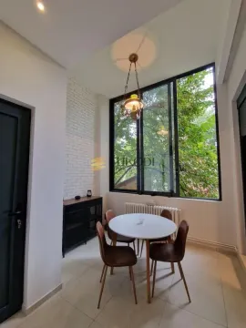 Dining area with a round table, four chairs and a large window overlooking greenery. - image 20