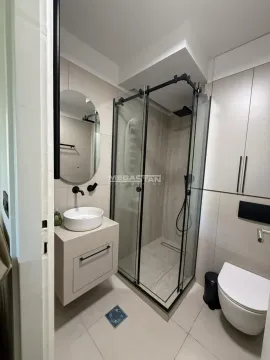 Modern bathroom with a walk-in shower, washbasin, and built-in cabinetry. - image 2