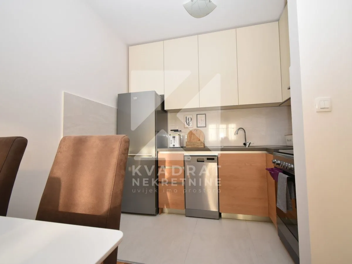 Compact kitchen with light-colored cabinets and a dining table.