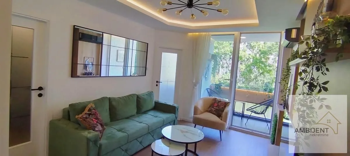 Living room with a green sofa, coffee tables, and access to the terrace.