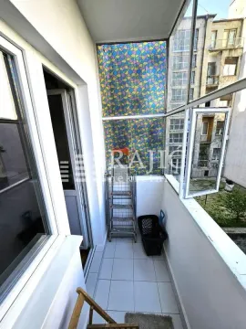 Glazed balcony with tiled floor and a view of surrounding buildings. - image 19
