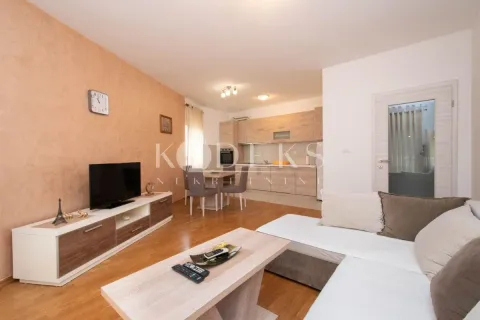 Living room with a sofa, TV, and dining area connected to the kitchen. - image 3