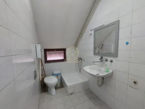 Small bathroom with a sink, toilet, shower tray, and a window in the attic. - image 10