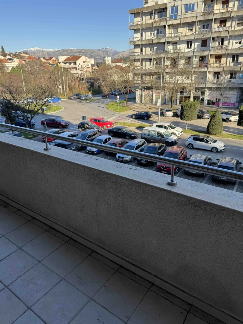 Pogled sa prostranog balkona na ulicu i parking ispred zgrade.