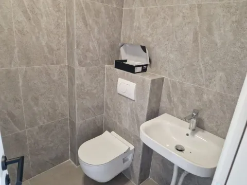 Manje kupatilo obloženo sivim keramičkim pločicama sa ugradnom šoljom i umivaonikom. - image 16