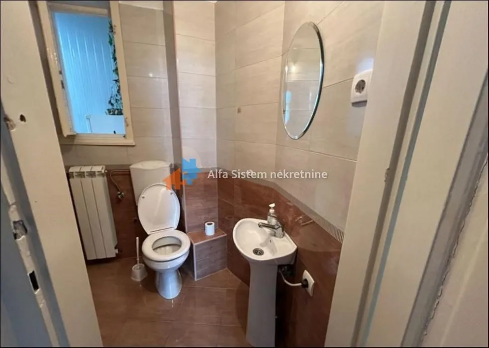 Manje kupatilo sa wc šoljom, umivaonikom i pločicama.