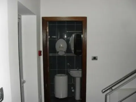 View of a small bathroom with dark tiles and a sink through an open doorway. - image 6