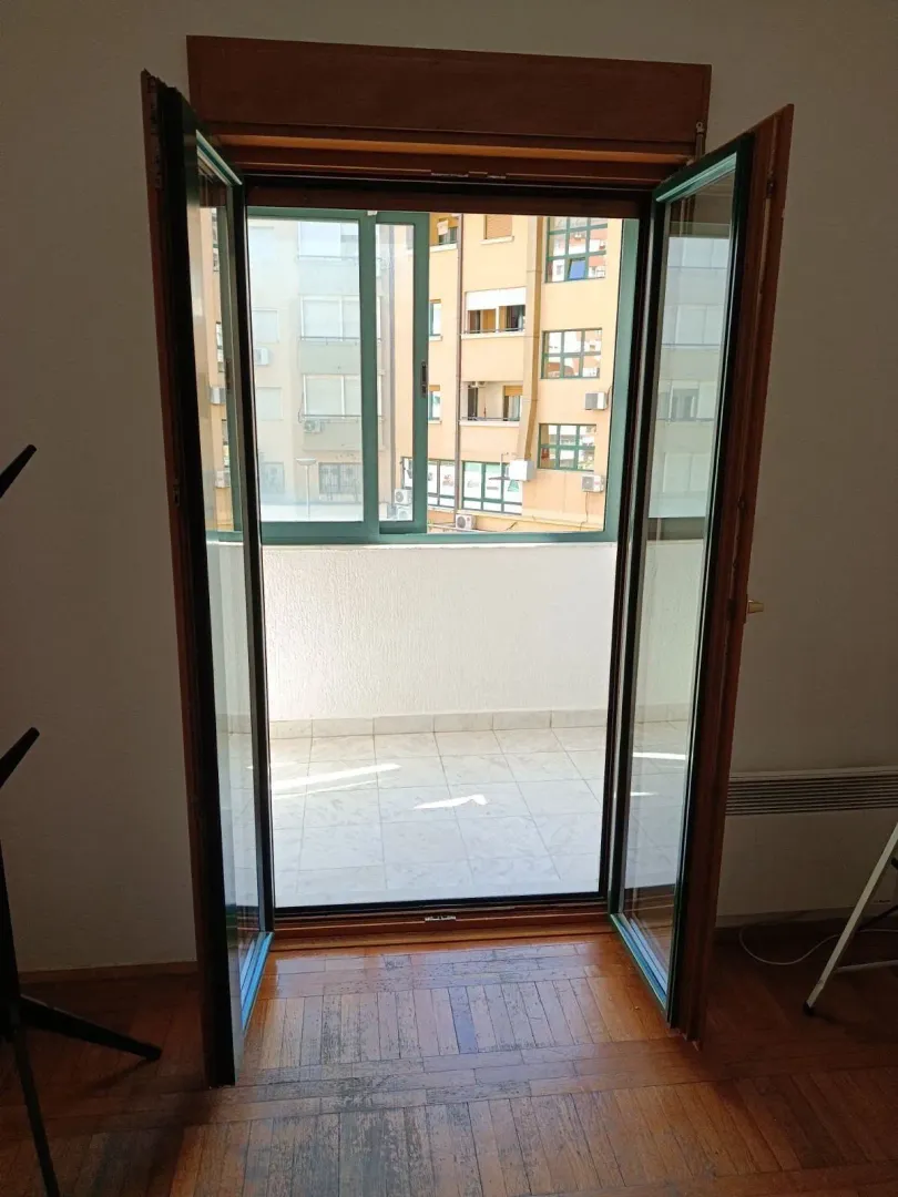 View through open balcony doors onto the terrace and surrounding buildings.