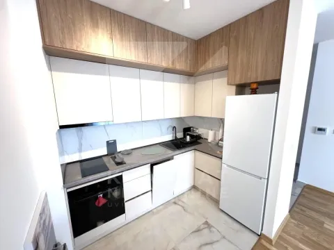 Modern kitchen with white units, wooden upper cabinets, and built-in appliances. - image 5