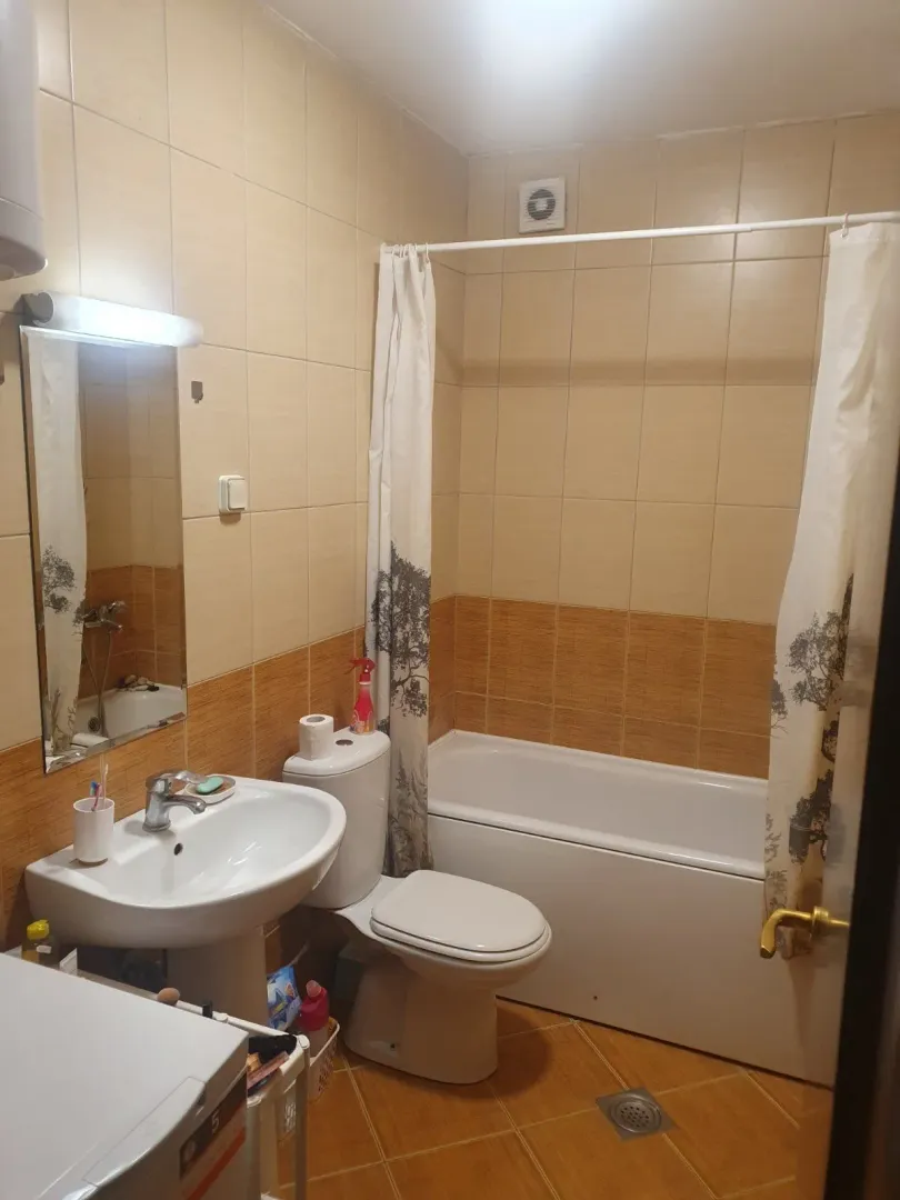A simple bathroom with a bathtub, sink, and beige ceramic tiles.