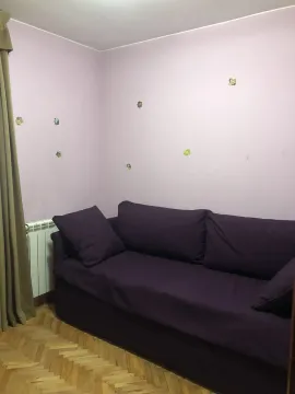 A room with a purple sofa, parquet flooring, and light-colored walls. - image 18