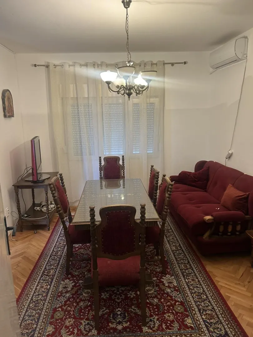 Dining area featuring a large table, chairs, and a red sofa.