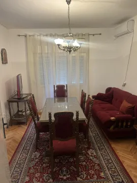 Dining area featuring a large table, chairs, and a red sofa. - image 11