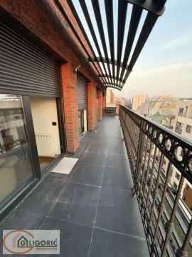 Prostrani popločani balkon sa metalnom ogradom i pogledom na grad. - image 13
