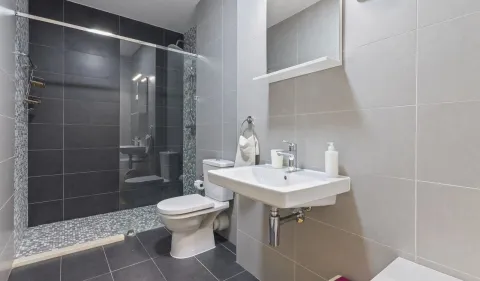 Moderne kupatilo sa tuš kabinom, umivaonikom i toaletom obloženo keramičkim pločicama. - image 5
