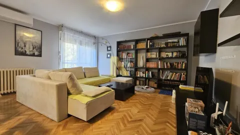 Dnevna soba sa ugaonom garniturom, velikom bibliotekom i parketom na podu. - image 2