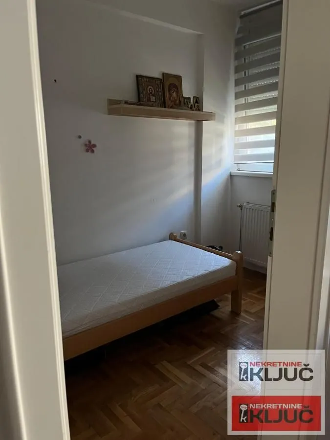 Smaller bedroom with a bed and a wall shelf.